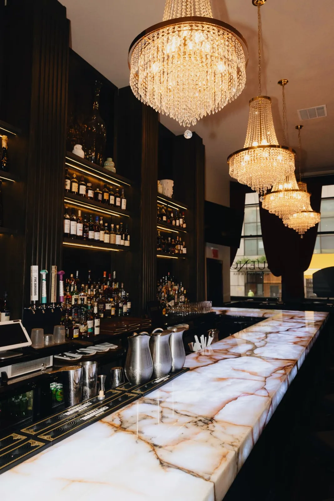 Crystal chandeliers above the backlit onyx bar