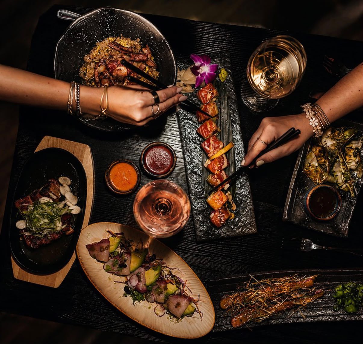 Sushi and shared plates arranged on a dark table