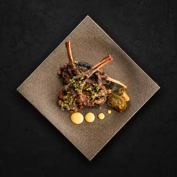 Grilled lamb chops finished with herbs on a square plate